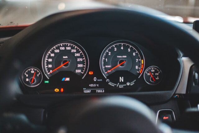 Cumpărător care inspectează compartimentul motor al unei mașini second-hand cu capota ridicată